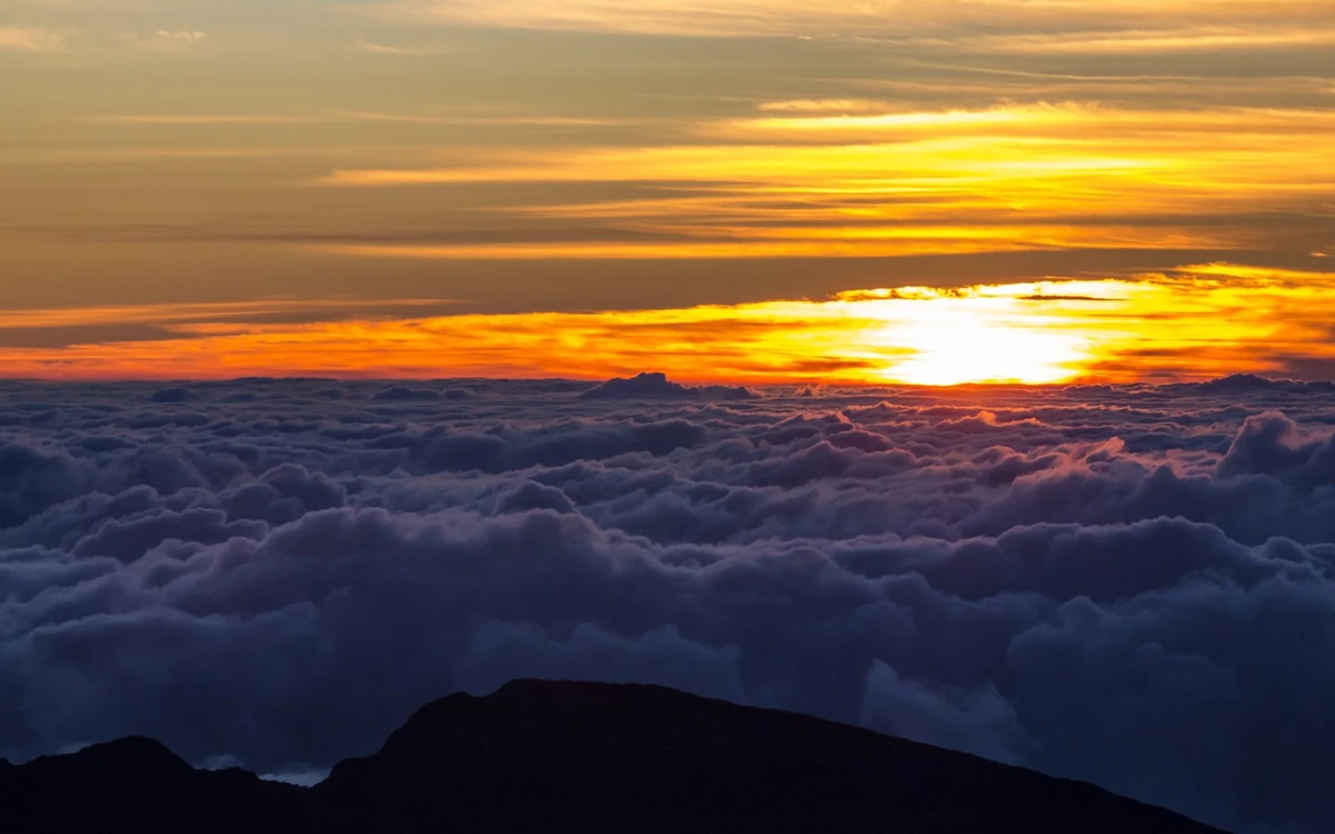 The visitor centre and summit rail at Haleakala with the sun low over the cloud layer